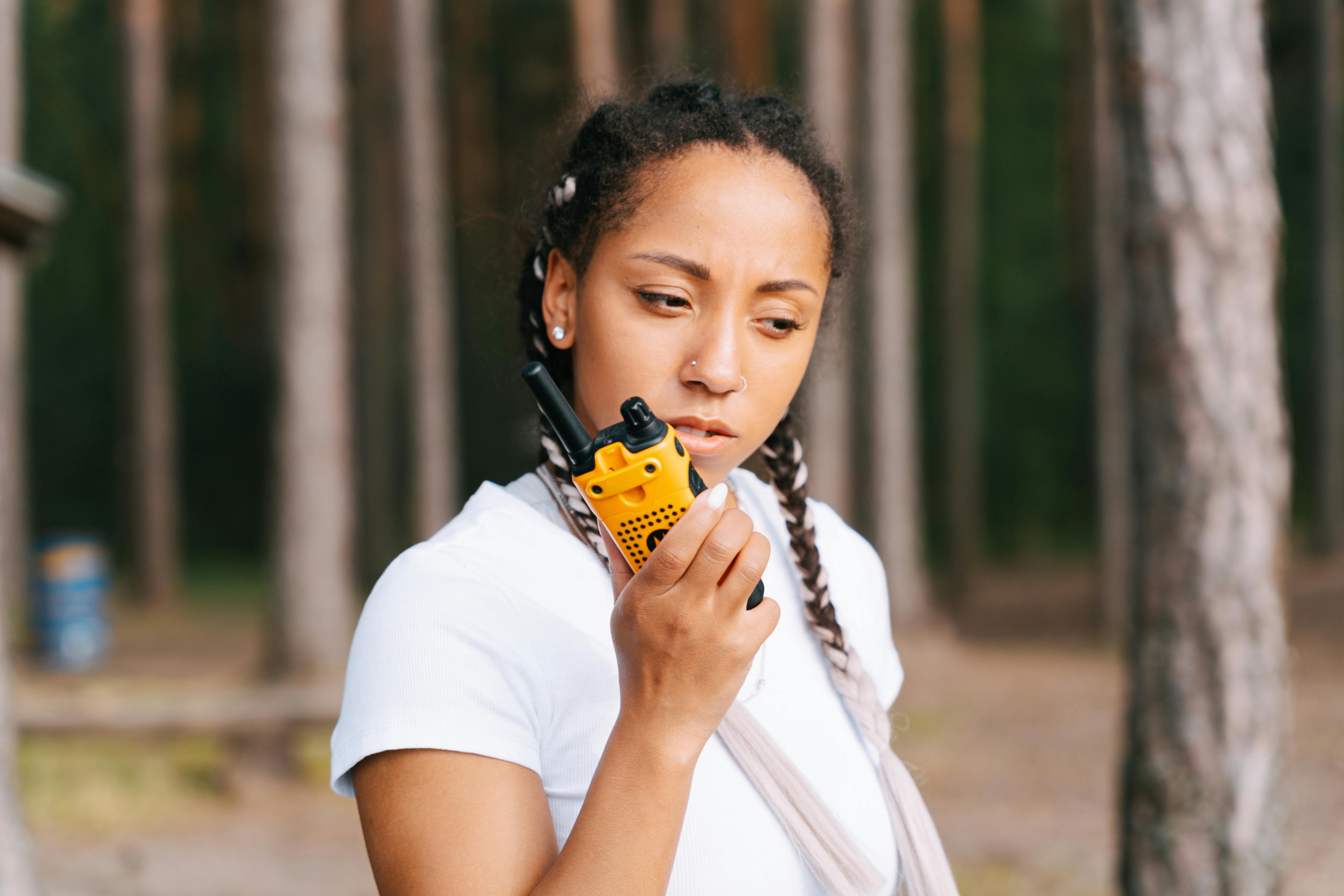 Female security team member using a two-way radio earpiece for clear communication in an outdoor environment.