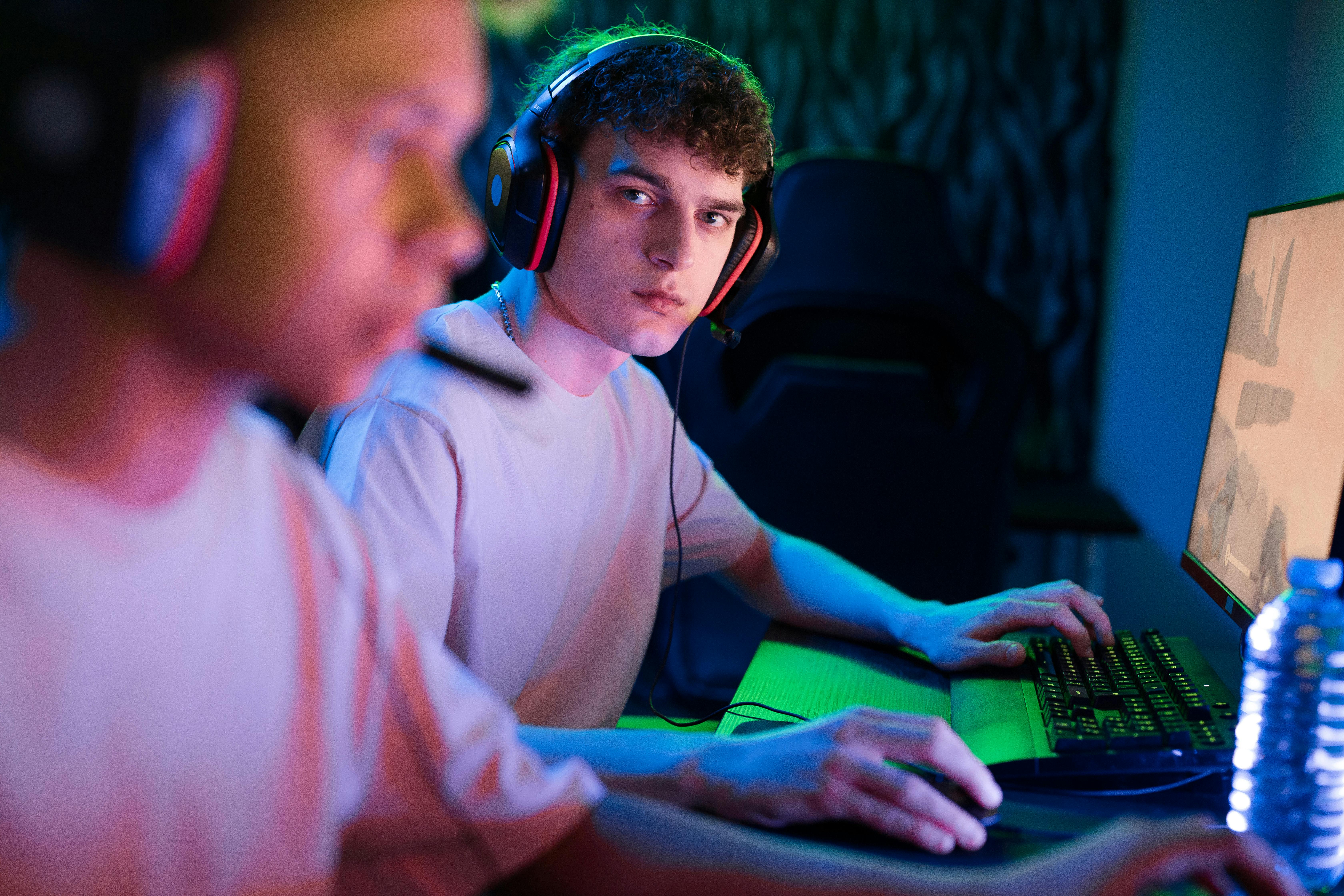 Focused gamers wearing noise-cancelling earpieces during an intense competitive gaming session.
