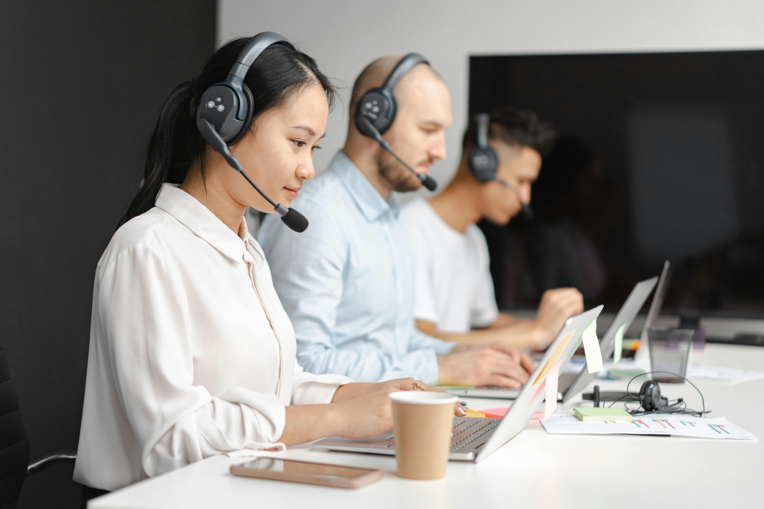 Office workers using noise-cancelling earpieces to improve focus and efficiency in a modern workplace.